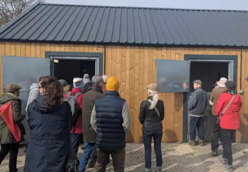 A Stables tour taking place at Wetherby Racecourse supporting the flat cap course walk raising money for Brain Tumour charity in March 2025. Attendees are viewing the stables and being shown what happens behind the scenes at the stable yard before racedays.