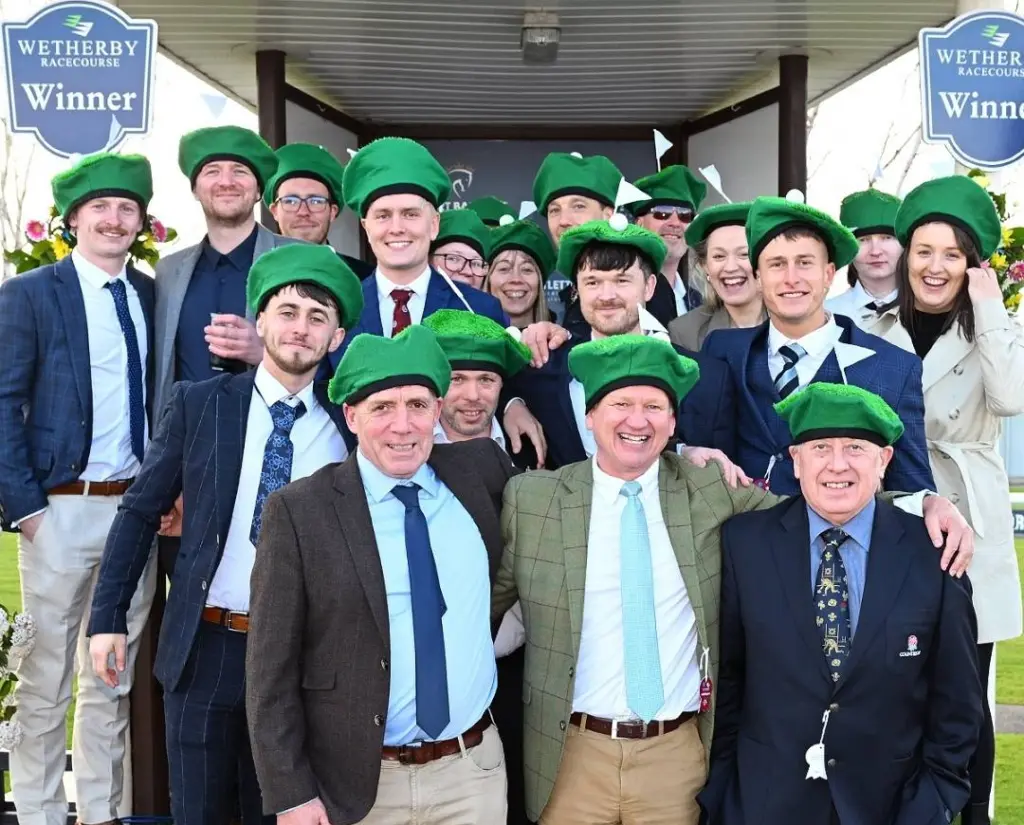 Group of Racegoers in the winners enclosure at Wetherby Racecourse in the parade ring wearing green beanie hats