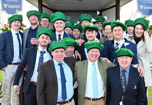 Group of Racegoers in the winners enclosure at Wetherby Racecourse in the parade ring wearing green beanie hats